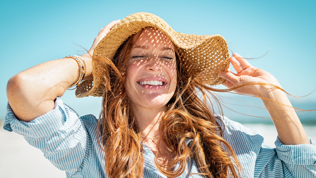 Woman in a sun hat enjoying summer, looking happy and free.