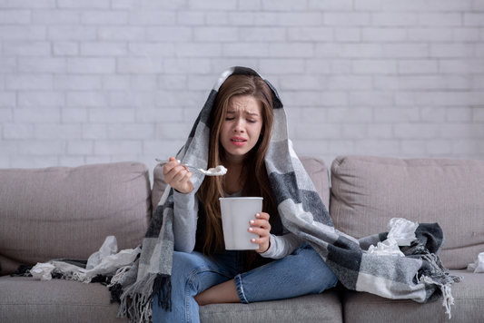 Woman sitting on a couch, eating ice cream and looking guilty.